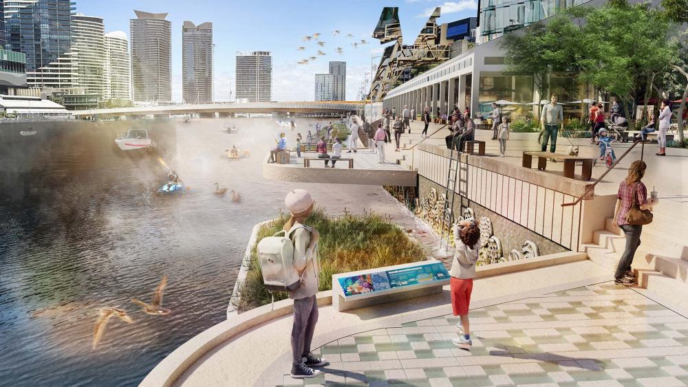 An artist’s impression of what the Seafarers Rest River Park Frontage might become. The image shows activity along the river, with boars, kayakers and swans enjoying the sunshine. As well as a promenade that wraps along the river's edge, passing ground-floor shops, with pedestrians using both the seats and observation decks to get the best look of the river. Birds fly through the sky, with skyscrapers seen in the distance.