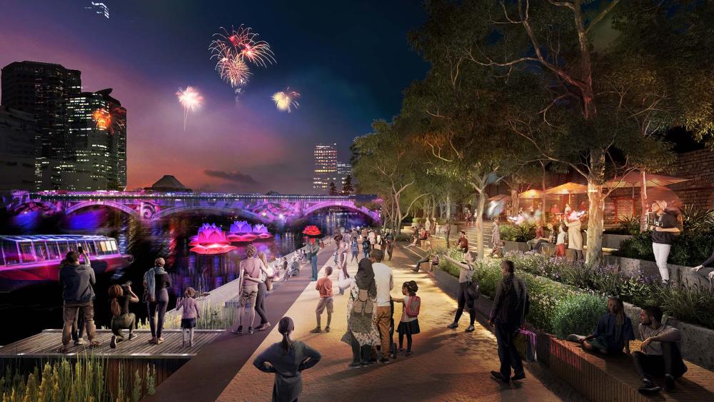 An artist’s impression of what Federation Wharf might become. The image shows people standing on the promenade, watching fireworks light up the night sky over an illuminated bridge.
